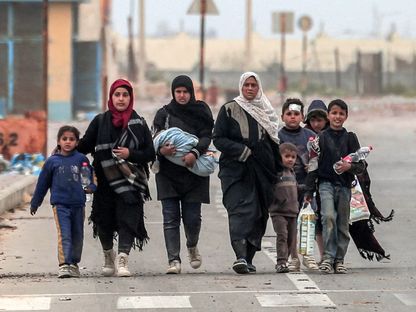 عائلة فلسطينية نازحة خلال فرارها من محيط مستشفى الشفاء في شمال غزة متجهة إلى مخيم النصيرات بوسط القطاع بينما يستمر القصف الإسرائيلي. 18 مارس 2024 - AFP