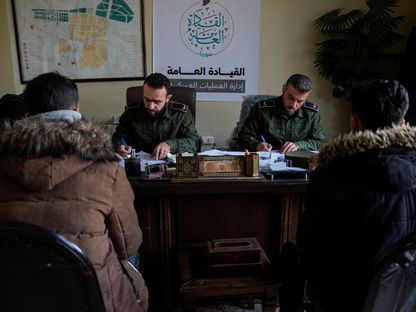 مقاتلون من جماعة هيئة تحرير الشام يتحدثون مع أعضاء في قوات الرئيس السوري السابق بشار الأسد في مركز للشرطة بمدينة حلب. 5 ديسمبر 2024 - reuters