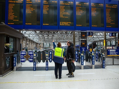 موظفة تساعد مسافراً بمحطة جلاسكو سنترال للقطارات وسط أكبر إضراب لعمال السكك الحديدية في بريطانيا منذ 30 عاماً  – 21 يونيو 2022 - Bloomberg