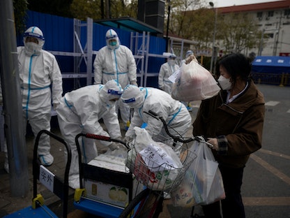 امرأة تقوم بتوصيل الطعام إلى مجمع سكني أثناء الإغلاق جراء تفشي كورونا في بكين. 28 نوفمبر 2022 - REUTERS