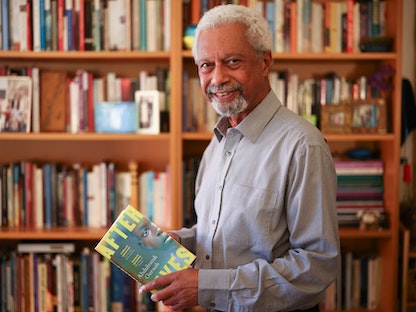 الروائي عبد الرزاق قرنح يحمل كتابه الجديد "آفتر لايفز" في مكتبة منزله في بريطانيا- 7 أكتوبر 2021 - REUTERS