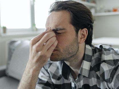 رجل مصاب بصداع شديد وألم بالرأس وحساسية للضوء والصوت - Getty Images