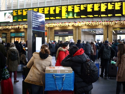 ركاب ينتظرون أسفل لوحة معلومات بمحطة قطار "كينجز كروس" بعد انتهاء إضراب عمال شبكة السكك الحديدية بلندن- 27 ديسمبر 2022. - REUTERS