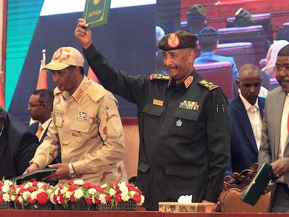 قائد الجيش السوداني عبد الفتاح البرهان يلوح بوثيقة الاتفاق الإطاري وبجواره محمد حمدان دقلو (يسار) إلى جانب القادة المدنيين  في الخرطوم. 5 ديسمبر 2022 - AFP