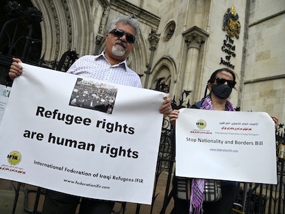متظاهران يحتجان خارج محاكم العدل الملكية في لندن، أثناء النظر في قضية قانونية بشأن وقف الترحيل المزمع لطالبي اللجوء من بريطانيا إلى رواندا. 10 يونيو 2022 - REUTERS