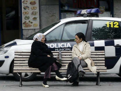 سيدتان تتحدثان أمام سيارة للشرطة وسط العاصمة الإسبانية مدريد - REUTERS