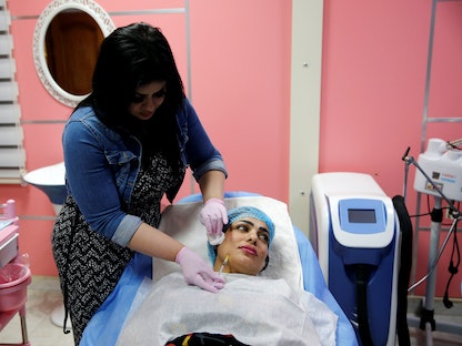 سيدة تخضع لحقن تعبئة الوجه لعلاج التجاعيد بأحد مراكز التجميل بالعاصمة العراقية بغداد. 24 مايو 2019 - REUTERS