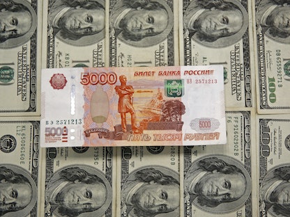 أوراق نقدية من فئة 100 دولار أميركي وفي الوسط ورقة الـ5 آلاف روبل روسي - REUTERS