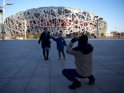 أشخاص يلتقطون صوراً أمام ملعب Bird’s Nest، مكان حفل الافتتاح والختام لدورة الألعاب الأولمبية الشتوية 2022، في العاصمة بكين، قبل عام من افتتاح الألعاب- 4 فبراير 2022 - AFP