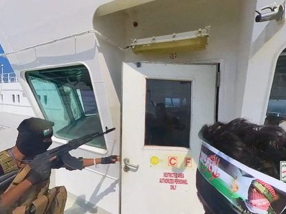 مقاتلون حوثيون يفتحون باب قمرة القيادة على سطح السفينة في البحر الأحمر. 20 نوفمبر 2023 - Reuters