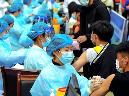 أعضاء طاقم طبي يدير إحدى عمليات التلقيح ضد فيروس كورونا في مقاطعة شاندونغ شرقي الصين- 30 مارس 2021 - AFP