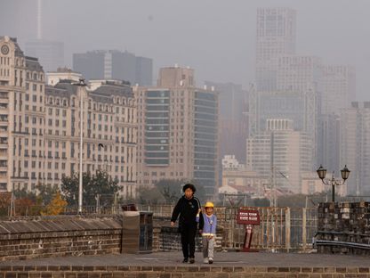 امرأة وطفل يسيران في حديقة مينج ديناستي بالعاصمة الصينية بكين بينما أصدرت السلطات تنبيهاً برتقالياً لتلوث الهواء الشديد. 31 أكتوبر 2023 - Reuters