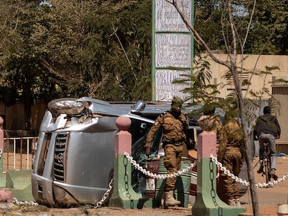عناصر الجيش في بوركينافاسو يسيرون بجانب سيارة مدمرة، في معسكر واجادوجو-  24 يناير 2022. - AFP
