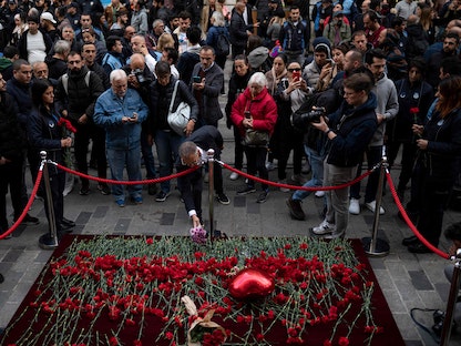 أحد المعزيين يضع الزهور وسط حشد بالحزن على ضحايا انفجار 13 نوفمبر في شارع استقلال وسط إسطنبول، تركيا، 14 نوفمبر 2022. - AFP