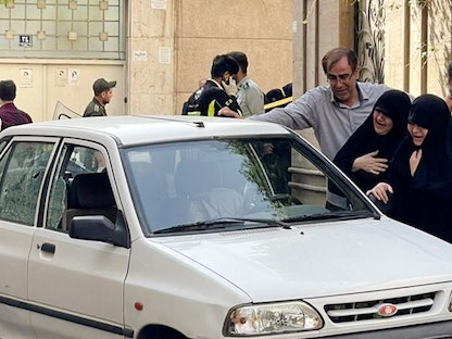 أفراد من عائلة العقيد في الحرس الثوري الإيراني صياد خدائي يبكون أمام سيارته بعد إطلاق النار عليه في طهران، إيران - 22 مايو 2022 - REUTERS