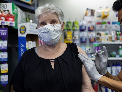 امرأة تتلقى لقاح "فايزر-بيونتك" المضاد لفيروس كورونا كجرعة تعزيزية في صيدلية في شوينكسفيل بولاية بنسلفانيا، 14 أغسطس 2021 - REUTERS