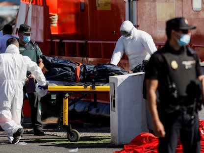 مسعفون ينقلون جثة مهاجر من سفينة تابعة لخفر السواحل الإسبانية في ميناء أرغوينيجوين بإسبانيا - 26 أبريل 2022 - REUTERS