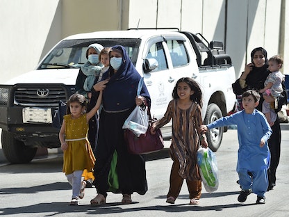 امرأة أفغانية وأطفالها يسيرون باتجاه بوابة الدخول الرئيسية لمطار كابول على أمل مغادرة البلاد بعد سيطرة طالبان على العاصمة، 28 أغسطس 2021 - AFP