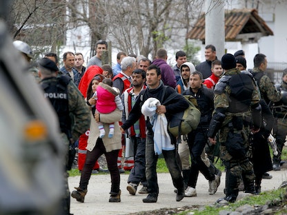 جنود مقدونيون يرافقون المهاجرين الذين عبروا الحدود بشكل غير قانوني من اليونان، إلى شاحنات عسكرية في قرية مويني، مقدونيا - 14 مارس 2016. - REUTERS