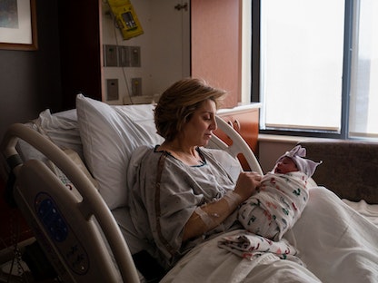 أم تحمل طفلها بعد ولادته في ولاية ميشيجان الأميركية. 1 فبراير 2022 - REUTERS