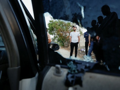مواطنون يقفون بجوار السيارة التي كان يستقلها الشبان الثلاثة، في أعقاب عملية إسرائيلية في جنين بالضفة الغربية المحتلة - 17 يونيو 2022. - REUTERS