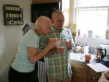مريضة بالسرطان وزوجها، يلقيان نظرة على بطاقة إرشادية للمصابات بسرطان الثدي، في مطبخ منزلهم في واشنطن، الولايات المتحدة - 25 مايو 2007 - REUTERS
