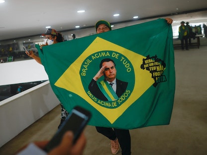 متظاهر في العاصمة برازيليا يحمل علم تتوسطه صورة للرئيس البرازيلي السابق جايير بولسونارو- 8 يناير 2023  - REUTERS
