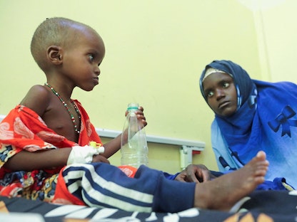 طفلة صومالية تعاني من سوء التغذية تشرب الماء من قارورة بينما تنظر والدتها إليها، في جناح الأطفال في مستشفى بنادير، في مقديشو، الصومال. 24 سبتمبر 2022 - REUTERS