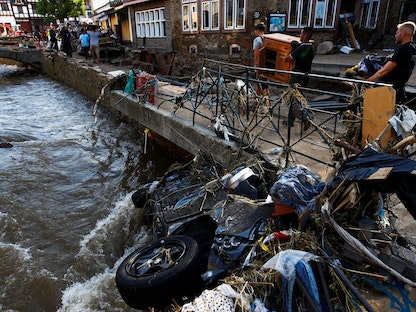 ضابط شرطة ومتطوعون يقومون بتنظيف الأنقاض في منطقة تضررت من الفيضانات الناجمة عن هطول الأمطار الغزيرة في باد موينستريفيل، ألمانيا. 18 يوليو 2021 - REUTERS