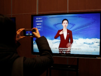 صحافي يصور شاشة تعرض نظام لغة إشارة رقمية مدفوعاً بنظام الذكاء الاصطناعي في أكاديمية بكين للذكاء الاصطناعي. 10 فبراير 2022 - REUTERS