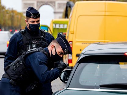 عناصر من الشرطة الفرنسية يقومون بتفتيش إحدى السيارات في شانزيليزيه - AFP