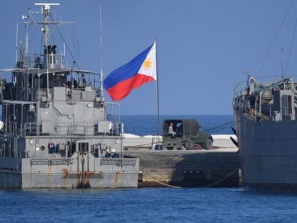 علم الفلبين يرفرف بجوار سفن تابعة للبحرية راسية في جزيرة ثيتو التي تحتلها الفلبين في بحر الصين الجنوبي المتنازع عليه. 21 أبريل 2023 - AFP