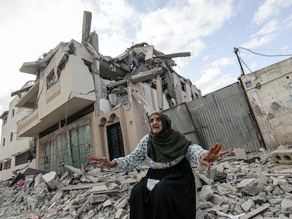 سيدة فلسطينية وسط أنقاض مبنى مدمر جراء غارة جوية إسرائيلية في خان يونس جنوب قطاع غزة. 13 مايو 2023 - AFP