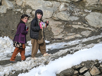 أطفال أفغان يمشون وسط الثلوج في العاصمة كابول - 6 يناير 2022 - AFP