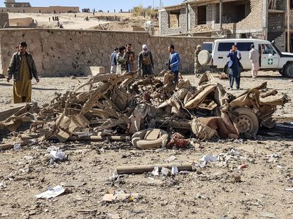 رجال أمن ومواطنون يعاينون موقع تفجير السيارة أمام مقرّ الشرطة الأفغانية في ولاية غور، 18 أكتوبر 2020 - AFP