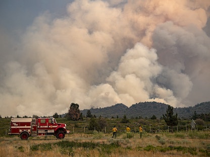 يراقب رجال الإطفاء المشهد بينما تستمر الحرائق في الاشتعال بولاية كاليفورنيا الأميركية - 1 يوليو 2021 - AFP