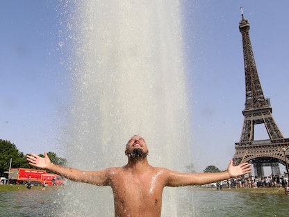 رجل يستريح في نافورة تروكاديرو على الجانب الآخر من برج إيفل في العاصمة الفرنسية باريس وسط درجات حرارة عالية قياسية تجتاح فرنسا وأوروبا الغربية- 18 يونيو 2022 - AFP
