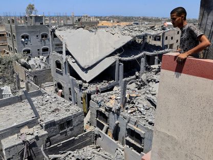 فلسطيني يتفقد المنازل المدمرة في دير البلح، وسط غزة، 23 يوليو 2025 - REUTERS