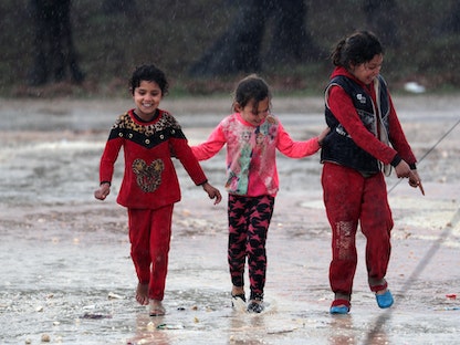 أطفال سوريون نازحون فروا من جنوب إدلب يسيرون تحت المطر في منطقة عفرين 7 فبراير 2020 - REUTERS