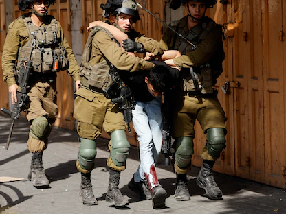 جنود إسرائيليون يعتقلون فتى فلسطينياً مصاباً في الخليل بالضفة الغربية المحتلة. 25 أكتوبر 2022 - REUTERS