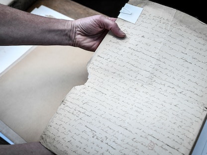 موظف يمسلك مخطوطة أصلية للكاتب الفرنسي الراحل مارسيل بروست قبل تجديدها في المكتبة الوطنية الفرنسية في باريس -  8 يوليو 2022 - AFP