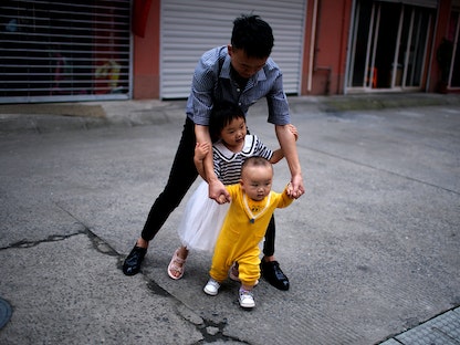 مواطن صيني يلعب مع طفليه في ضواحي شنغهاي. 3 يونيو 2021 - REUTERS