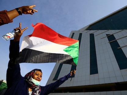 امرأة تلوّح بالعلم السوداني أثناء مشاركتها في مظاهرة أمام المجلس التشريعي في العاصمة الخرطوم لدعم الانتقال الديمقراطي - 30 سبتمبر 2021  - AFP