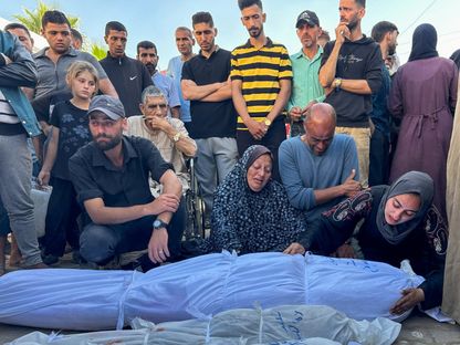 أسر فلسطينية بجوار جثامين ضحايا قتلتهم غارة إسرائيلية في دير البلح وسط قطاع غزة. 31 مايو 2024 - REUTERS