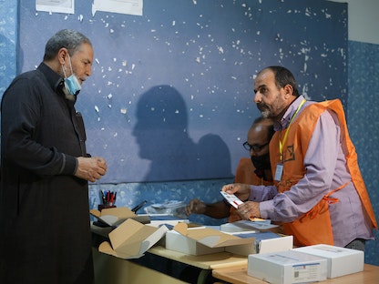 رجل ليبي يتلقى بطاقته الانتخابية في أحد مراكز الاقتراع بالعاصمة طرابلس - 8 نوفمبر 2021 - REUTERS