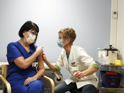 طبيبة متخصصة تتلقى جرعة من لقاح "فايزر- بايونتيك" في إحدى المستشفيات - AFP 