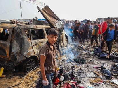 فلسطينيون في موقع الغارة الإسرائيلية على مخيم النازحين غربي مدينة رفح والتي أودت بحياة العشرات. 27 مايو 2024 - AFP