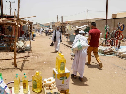 سودانيون يمرون أمام محل لبيع المواد الغذائية على بعد 350 كيلومتر من العاصمة الخرطوم. 15 أغسطس 2023 - AFP