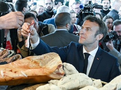 الرئيس الفرنسي إيمانويل ماكرون يحصل على بعض الطعام خلال زيارة لمدينة باربازان ديبات في فرنسا- 29 أبريل 2022 - REUTERS