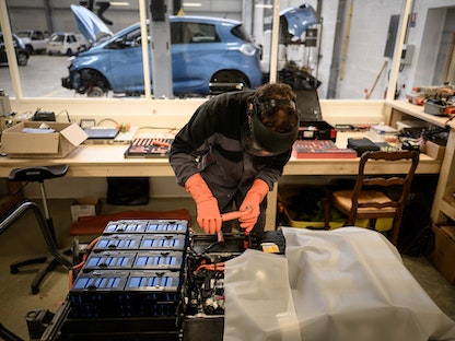 ميكانيكي يعمل على وحدة البطارية لسيارة كهربائية في المرآب الإلكتروني Revolte المتخصص في إصلاح السيارات الكهربائية في كاركفو غربي فرنسا. 30 نوفمبر 2022 - AFP